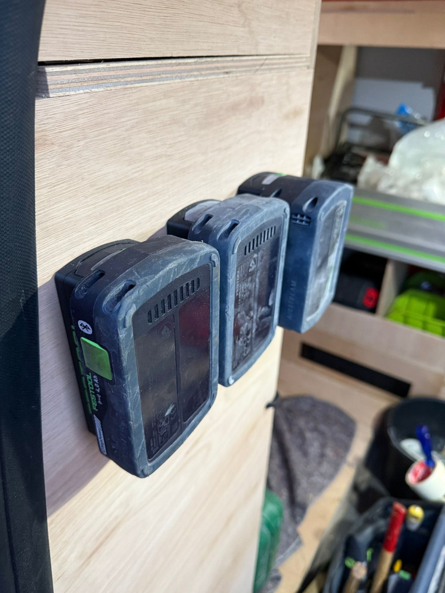 Georganiseerde werkplaats met meerdere Festool accuhouders aan de muur